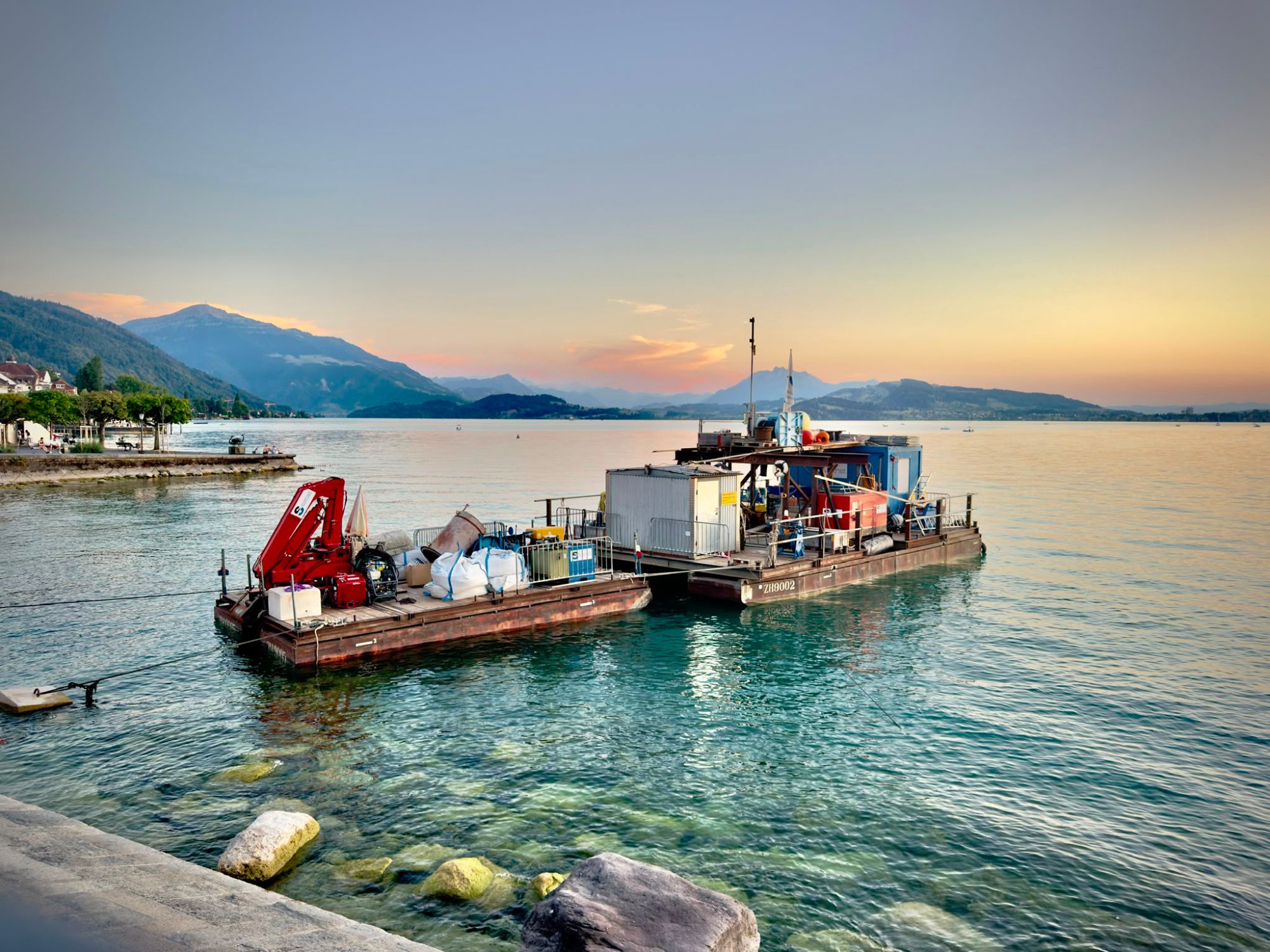 A boat moored off a lake path, mountains behind it at sunset